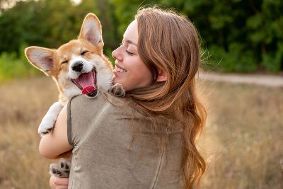 Eine Frau und ein Hund schauen fröhlich in die Kamera.